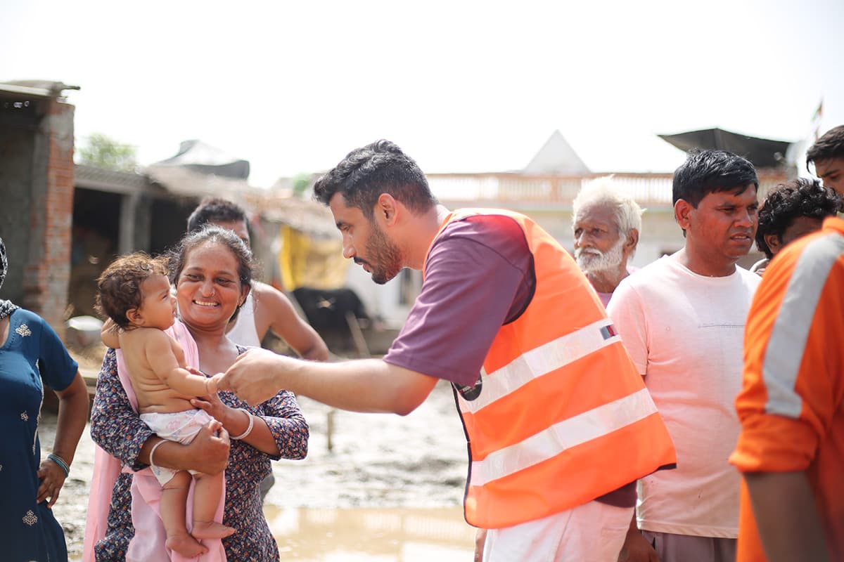A volunteer greeting a mother and child during a relief visit