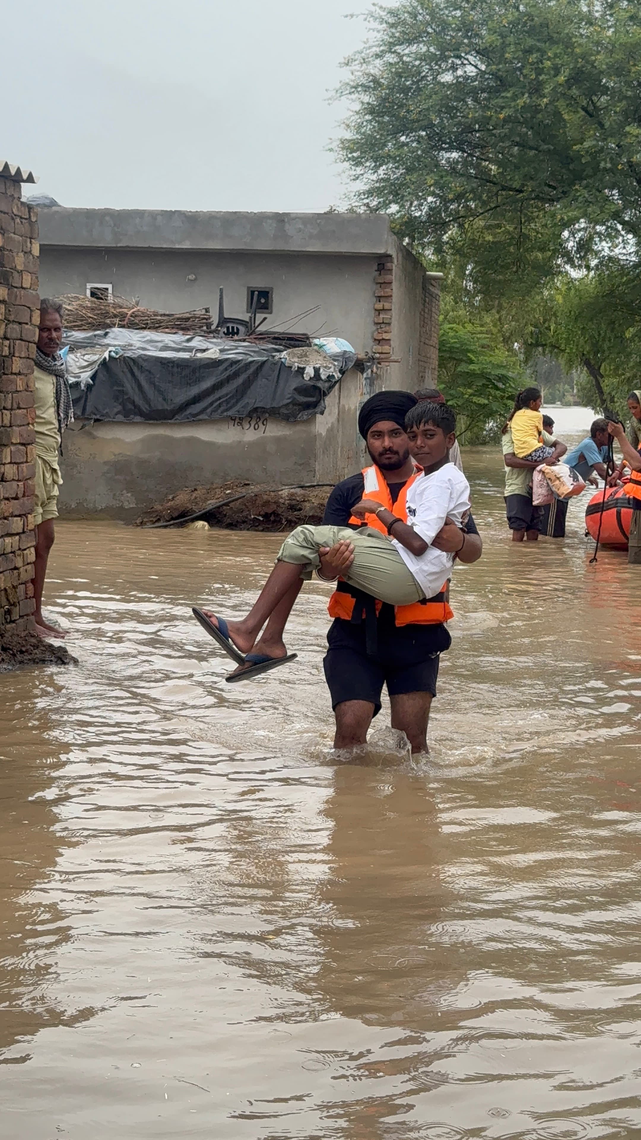 Youth responder carrying a child through floodwaters to safety